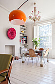 Orange lamp in dining room with mirrored table and wooden floor