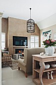 Wooden console table against back of sofa, pendant lamp with bird-cage lampshade and flatscreen TV in lounge