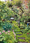 Stepping stone path through flowering garden leading to idyllic seating area
