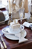 White place setting with vintage-style paper decoration, Champagne flute and silver candlestick on wooden table