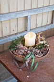 Pillar candle, stag ornaments and pine cones arranged in bowl