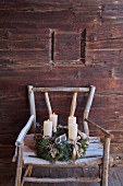 Vintage-style Advent wreath on rustic wooden chair against cabin wall