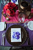 Festive place setting with orchid bloom on table set for Indian wedding