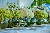 Glass vases of various flowers on wedding dinner table