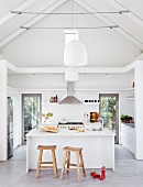Open-plan kitchen and rustic bar stools at white counter