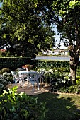 Idyllischer Gartenplatz mit weißen nostalgischen Metallstühlen und romantischem Flair