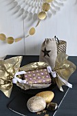 Christmas present wrapped in gold paper and gold-painted pebbles