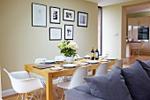 weiße Klassiker Schalenstühle um gedeckten Tisch in offenem Wohnraum mit pastellfarben getönten Wänden