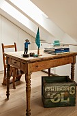 Stacked books and comic figurine on vintage wooden table above printed wooden crate in attic room