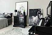 Piano, cabinet and photo of horse leant against wall in monochrome bedroom