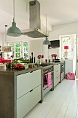Free-standing kitchen counter with integrated gas cooker under extractor hood in country-house-style kitchen