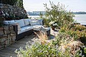 Modern outdoor sofa with pale cushions on sunny terrace with view of the Elbe