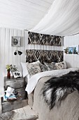 Bed with canopy and fur blanket in cosy bedroom