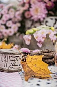 Herbstdeko mit Dekoband-Rolle, Ahornblatt und Chrysanthemen