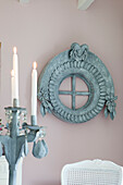 Lit candles in cardboard candelabra in front of cardboard faux window-frame with ornate decorations