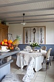 Dining area in front of large picture of cutlery on wall; fruit basket on kitchen counter in foreground
