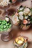 Bowl with green wedding almonds, festive flower arrangement and lantern