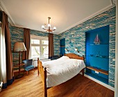 Wood-framed double bed against wall with patterned wallpaper and shelves in blue-painted niches