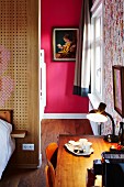 Desk in bedroom and view of artwork on hot pink wall seen through open doorway