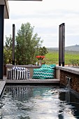 Small pool with water spout and comfortable beanbag on wooden terrace