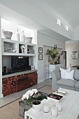Vases and TV on fitted shelving above firewood niche and vintage accessories in seating area