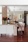 Floral armchairs at modern kitchen counter clad in stone strip tiles