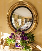 Festively set dining table reflected in antique convex mirror above mantelpiece in dining room of private house in Suffolk, England