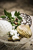 Christmas arrangement with snowberries and kermes-oak acorns on glass cake stand