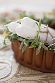 White candles in planted container on embroidered vintage tablecloth