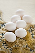 weiße Eier auf bestickter Vintage-Tischdecke mit Blumenmotiv