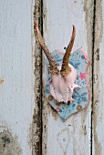 Hand-decorated deer antlers on pale blue wooden plaque on shabby-chic board wall