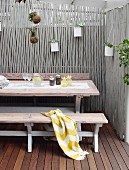 Vintage table and benches and planters hanging from grey-painted wooden screen