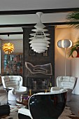 White leather armchairs and classic pendant lamp in front of metal fireplace in cosy retro interior