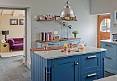 Kitchen island with blue base units and marble and walnut worksurfaces