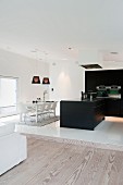 White dining area and black kitchen in open-plan interior