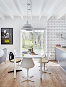 Retro shell chairs around white table in open-plan interior with terrace doors