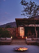 Twilight atmosphere in outdoor seating area with fire in fire bowl on terrace