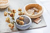 Crocheted, pastel baskets decorate with dried hop flowers and clay tablets