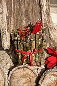 Red candles and berries in plant pot wrapped in twigs