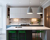 Kitchen with white counter-height table and green-painted bar stools in traditional interior