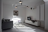 Three-armed designer lamp in white minimalist living room with patterns of light and shade on floor