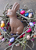 Chocolate Easter bunny in nest of twigs and chocolate eggs