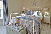 White, metal double bed and tray on wicker trunk in rustic bedroom