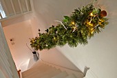 View down staircase with festively decorated handrail in rustic stairwell