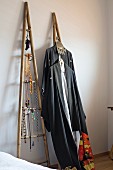 Jewellery and clothing hung on ladder-style wooden frames leant against wall