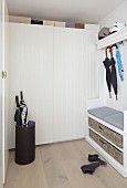Cloakroom with hat rack, bench, umbrella stand, umbrellas hung from coat rack and white fitted wardrobes