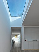 White kitchen counter and hallways with large skylight showing blue sky