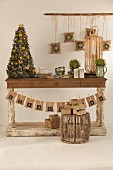 Weihnachtsbäumchen auf rustikalem Holztisch und Adventskalender aus Papiertütchen