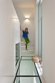 Girl walking down stairs onto landing with glass floor