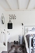Animal-skin rug on grey bedroom floor and classic black Hang-It-All coat rack on white wall